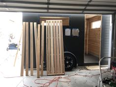 the inside of a garage with some wooden boards in it and a car parked next to it