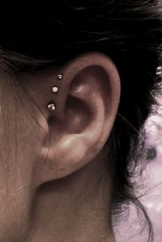 a woman's ear with three piercings on it