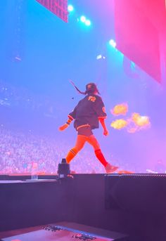 a person standing on top of a stage in front of a crowd at a concert