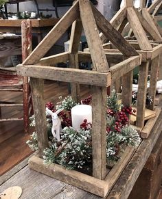 a small wooden house with candles and greenery in the center, on top of a table