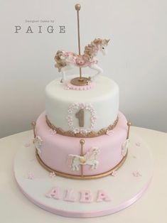 a pink and white birthday cake with a horse on top that says pagie 1st birthday