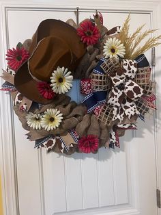 a cowboy hat is hanging on the front door with burlocks and daisies