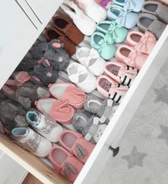 a drawer filled with lots of baby shoes on top of a carpeted kitchen floor