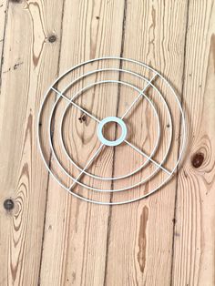 a circular metal object sitting on top of a wooden floor next to wood planks