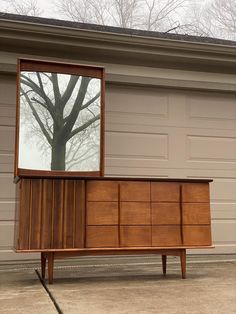 a large wooden dresser sitting in front of a garage door with a mirror on it