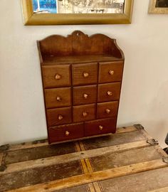 an old wooden dresser sitting on top of a hard wood floor next to a painting