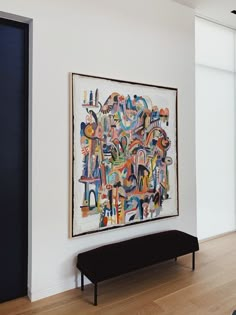 an abstract painting hangs on the wall next to a bench