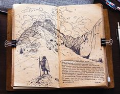 an open book with drawings on it sitting on top of a table next to a pen