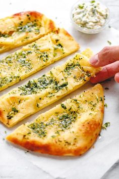 four pieces of pizza with cheese and herbs on them being held by someone's hand