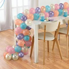 a table with some balloons on it and two chairs in front of the table,