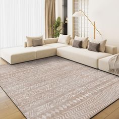 a living room with a large sectional couch and pillows on the floor in front of a window