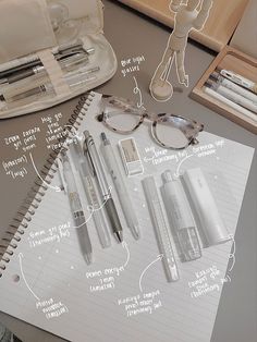 an open notebook with various items labeled in english and french on it, including glasses, pens, pencils, and paper