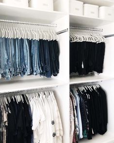 an organized closet with clothes hanging on shelves and bins full of folded shirts, pants and sweaters