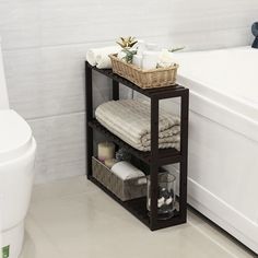 a white bath tub sitting next to a wooden shelf filled with towels and other items