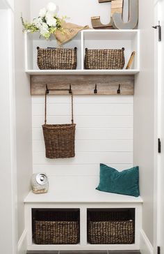 a white mud room with baskets on the shelves