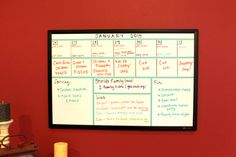 a dry erase board mounted to the side of a red wall