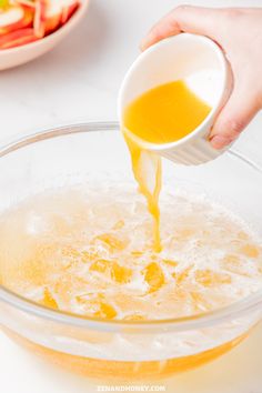 someone pouring orange juice into a glass bowl