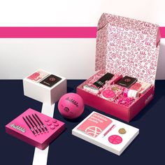 pink and white boxes with various items in them sitting on a table next to each other