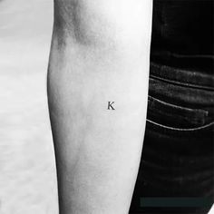 a person with a small letter tattoo on their left arm and the word k in black ink