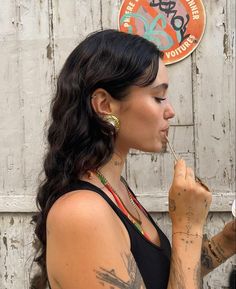 a woman with tattoos on her body is brushing her teeth and looking off to the side