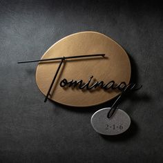 a round wooden sign with the word tominag written on it and two needles sticking out of it