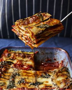 a person is lifting some lasagna out of the casserole dish