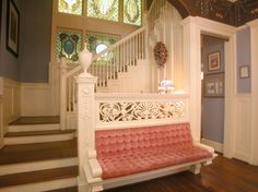 a pink couch sitting on top of a wooden floor next to a stair case in a house