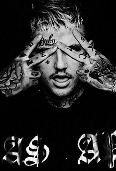 a man with tattoos covering his eyes and hands behind his head is looking at the camera