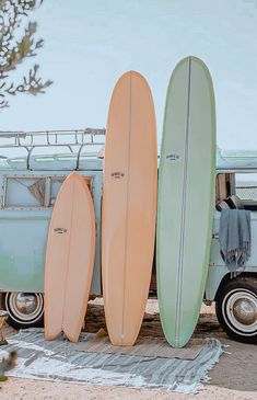 three surfboards are lined up next to an old vw bus