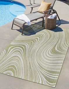 a chair sitting next to a swimming pool on top of a green and white rug