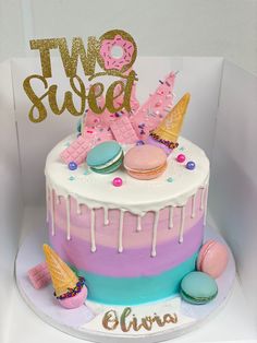 a two tiered cake decorated with macaroons, donuts and sprinkles