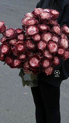 a person holding a bunch of flowers in their hands on the side of the road