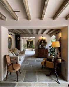 a living room with stone flooring and exposed beams on the ceiling, along with two chairs