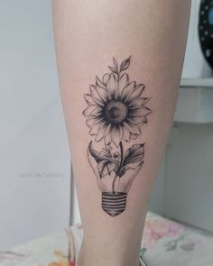 a sunflower in a light bulb tattoo on the leg