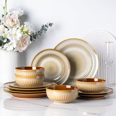 a white vase filled with flowers and plates