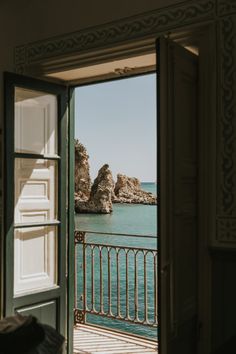 an open door leading to the ocean with rocks in the water and a rock outcropping