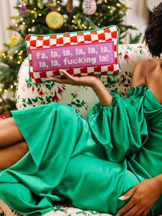 a woman in a green dress is sitting on a couch with a red and white pillow