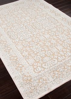 a white rug with an intricate design on the floor in a room that has wood floors