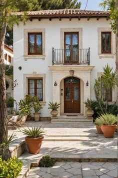 a house with potted plants in front of it and stairs leading up to the door