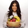 a woman holding a bowl full of fruit