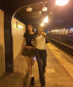 two women walking down a train platform at night