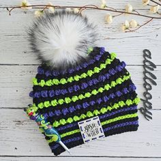 a black, green and blue striped hat with a white pom - pom