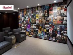 a room with two gray chairs and a large wall covered in movie posters