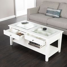 a white coffee table with two drawers and a glass top in front of a couch