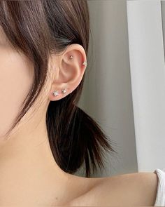 a close up of a person wearing an earring with two stars on the side