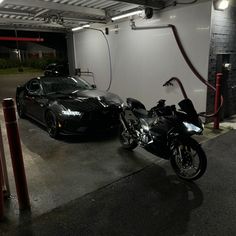 two motorcycles parked next to each other in front of a garage with a black car