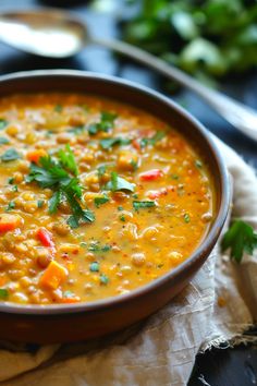 A bowl of lentil soup garnished with chopped parsley and accompanied by a spoon and herbs in the background. Glazed Meatballs, Spicy Appetizers, Curry Spices, Lentil Curry