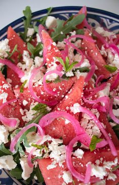 watermelon salad with feta cheese and red onions on a blue and white plate