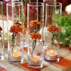 four vases with flowers and candles on a table