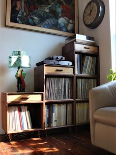 a living room filled with furniture and a clock on the wall next to bookshelves